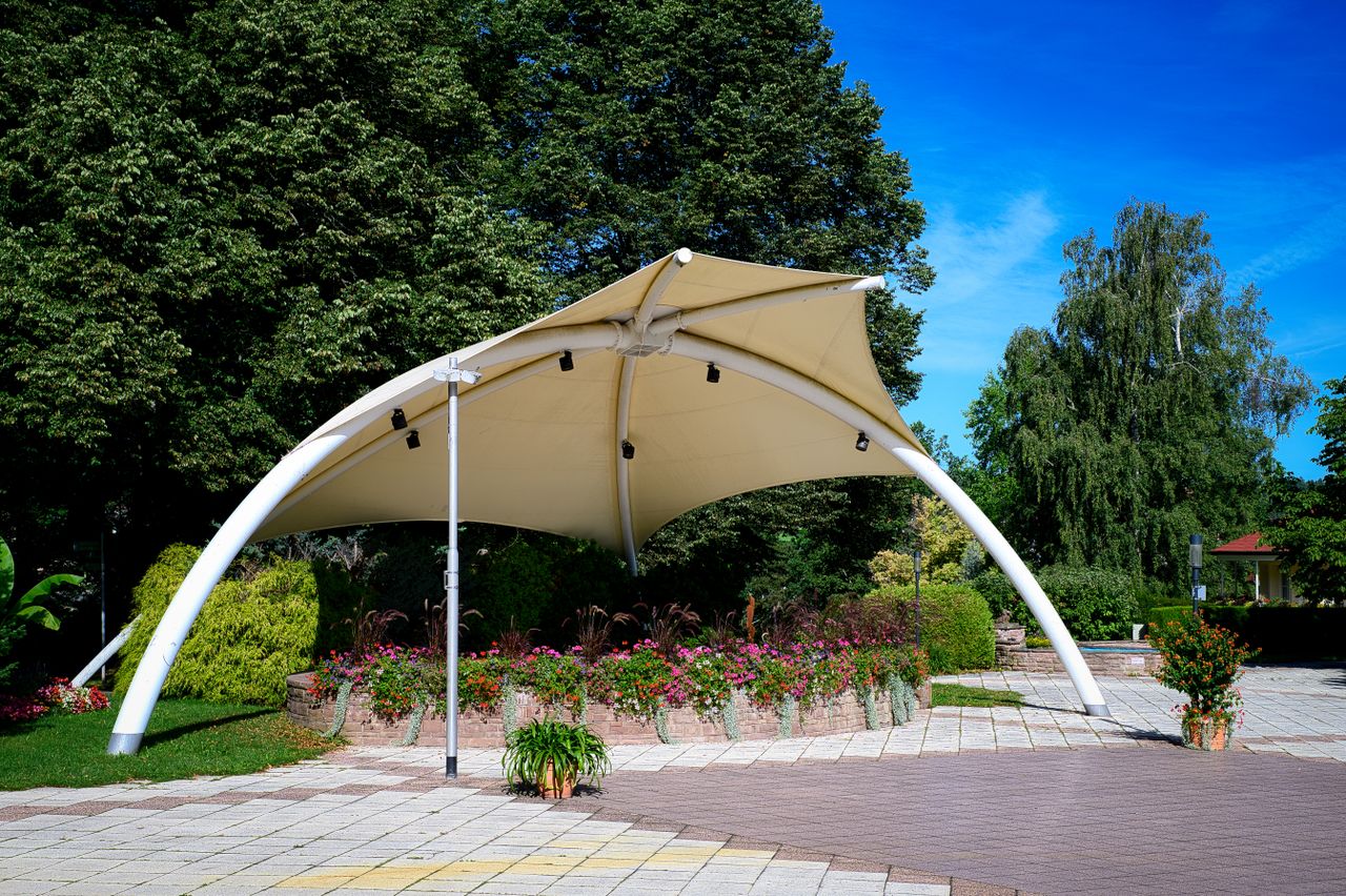 A modern pavilion surrounded by colorful flowers in a scenic park in Schömberg, Germany.